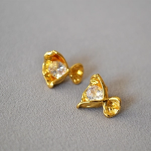 Macro shot of gold-plated pleated flower earrings with sparkling round cubic zirconia stones