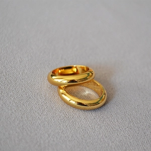 Close-up of dual minimalist gold-plated brass rings with a polished mirror finish