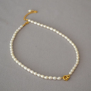Detail of freshwater pearl necklace featuring a golden double-loop pendant and lobster clasp