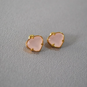 Macro shot of heart-shaped pink gemstone stud earrings with gold-plated claw setting