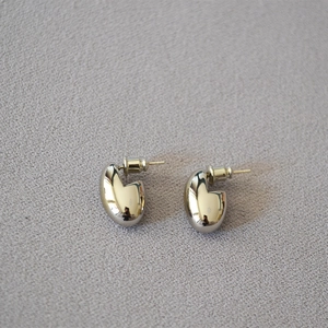 Macro shot of silver-plated oval egg-shaped earrings with a polished mirror finish