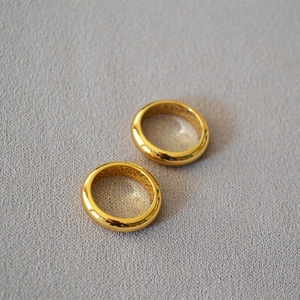 Close-up of minimalist gold-plated brass rings set on textured grey fabric