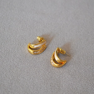 Macro detail of gold-plated double-layer C-hoop earrings with white enamel and zircons