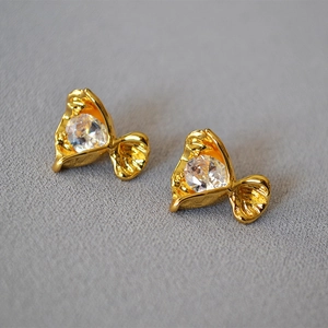 Macro shot of gold pleated bezel earrings featuring round multifaceted zircon stones