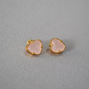 Macro shot of heart-shaped pink gemstone earrings with elegant gold-plated claw setting
