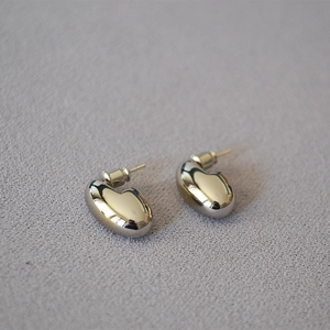 Macro view of minimalist bean-shaped gold-plated stud earrings with polished mirror finish