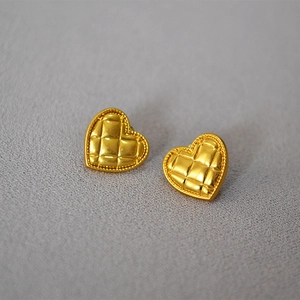 Macro shot of gold quilted heart studs with delicate beaded edges and vintage texture