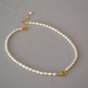 Elegant freshwater pearl necklace with double gold-plated rings on grey textured fabric