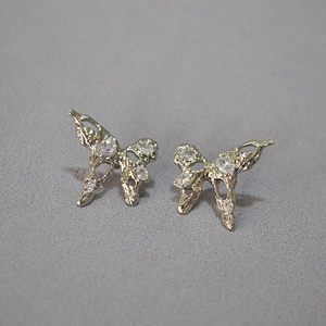 Detailed view of silver butterfly earrings with textured metal and sparkling zircons