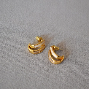 Detailed macro of white enamel and zircon stones on these gold plated J-hoop earrings
