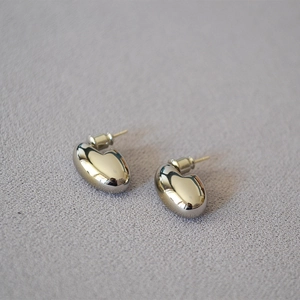 Macro shot of minimalist egg-shaped stud earrings with high-polish metallic finish