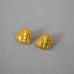 Detail of vintage heart-shaped brass earrings with quilted pattern and beaded edge