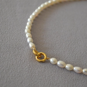 Macro detail of oval freshwater pearls and golden clasp on an elegant necklace
