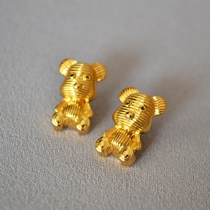 Detailed view of golden striped bear stud earrings with a textured ribbed metal surface
