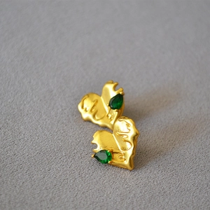 Detail of vintage molten heart brass studs with emerald teardrop stones and matte finish