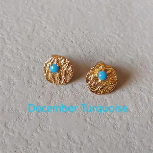 Detailed macro view of gold textured earrings set with a round December turquoise stone