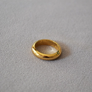Detailed view of a gold dome ring with a mirror-polished finish on grey fabric