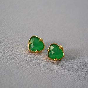 Macro detail of faceted green agate stud earrings set in vintage gold-plated brass claws