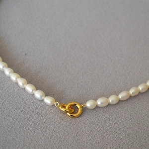 Detailed macro of freshwater pearl necklace with polished gold circular metal clasp