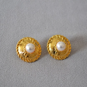 Close-up of vintage gold disc earrings with white pearl center and twisted rope texture