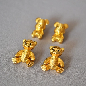 Macro shot of gold cute bear stud earrings with horizontal striped texture and black eyes