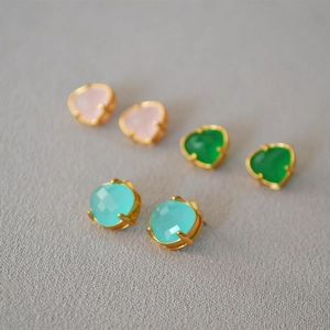 Detailed shot of gold-plated gemstone studs in heart and round shapes with vibrant colors