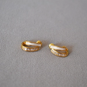 Detailed close-up of gold stud earrings with white enamel and sparkling zircon rows