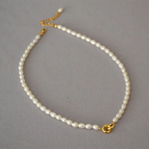 Detail of freshwater pearl necklace featuring interlocking gold rings and lobster clasp