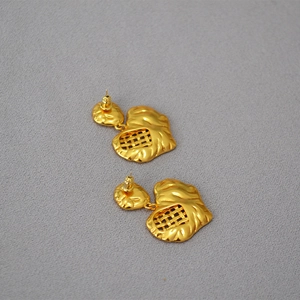 Dettaglio di orecchini vintage placcati oro con trama intrecciata e forma a cuore organico