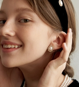 Detail of floral earring with oval pearl and zircon wreath on elegant model