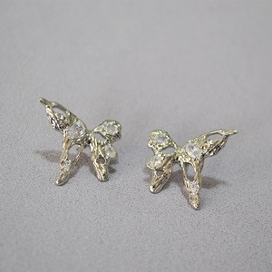 Close-up of silver butterfly earrings with lava texture and sparkling zircon stones