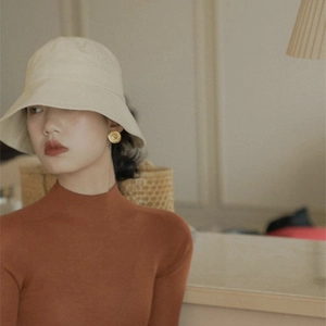 French vintage gold camellia disk earrings paired with a beige wide-brim canvas bucket hat