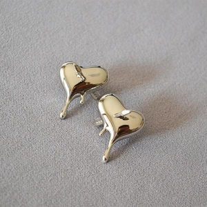 Boucles d'oreilles cœur en lave fluide argentée en laiton poli sur fond gris texturé