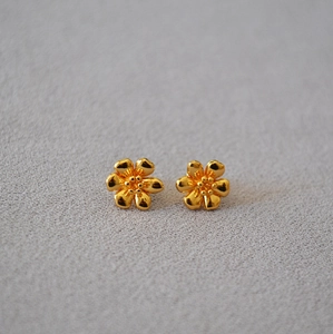 Detailed view of handmade enamel camellia stud earrings in polished golden finish