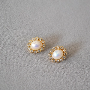 Detail view of oval pearl earrings with sparkling zircon wreath in gold finish