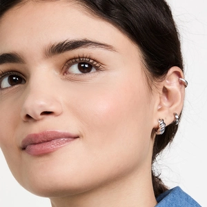 Close-up of stacked silver twisted rope hoop earrings and ear cuff on female model