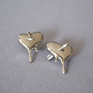 Boucles d'oreilles cœur de lave argentées avec flèche sur tissu gris