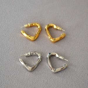Detailed view of twisted heart-shaped earrings in polished gold and silver finishes