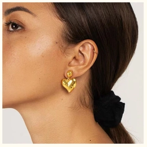 Vintage hammered gold heart earrings with irregular texture on elegant female model