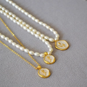 Detail of freshwater pearl necklace with vintage gold floral relief coin pendant