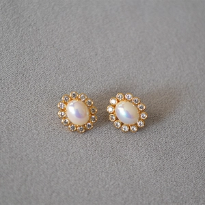 Detailed view of vintage gold stud earrings with oval pearls and CZ diamond wreaths