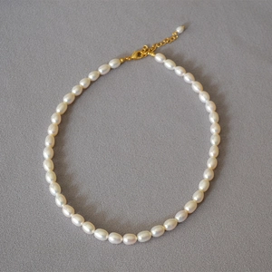 Dettaglio macro della collana di perle d'acqua dolce ovali con chiusura a moschettone dorata
