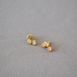 Macro shot of gold-plated stud earrings featuring three clustered round zircon stones