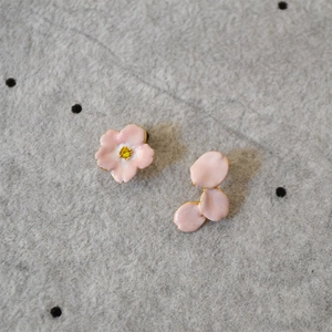 Detail of asymmetrical pink enamel cherry blossom earrings with gold trim and yellow stones