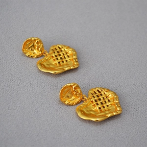 Dettaglio di orecchini a cuore placcati oro con trama intrecciata e bordi pieghettati