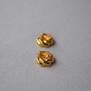 Detailed view of gold plated croissant twist earrings with a vintage texture