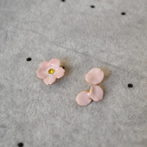 Detail of pink enamel cherry blossom asymmetric studs with yellow gemstone centers