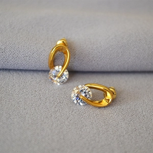 Close-up of golden teardrop hollow earrings with sparkling zircon stones in a macro view