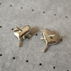 Détail des boucles d'oreilles cœur en argent avec effet fondu et flèche traversante