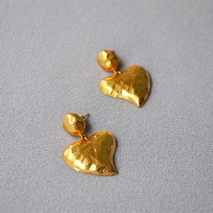 Retro hammered gold heart earrings with textured surface and 925 silver needle on gray